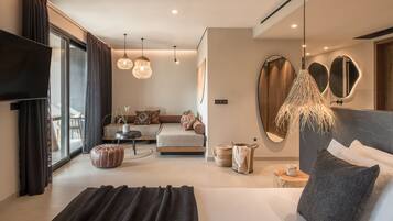 A modern hotel room with a large bed, a sofa, a dining area, and a TV.