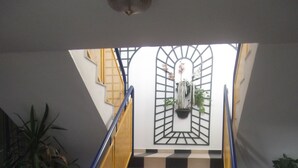 A staircase with alternating black and white tiles, blue handrails, and potted plants on either side. - Rev'Hotel Coignières (Coignieres)