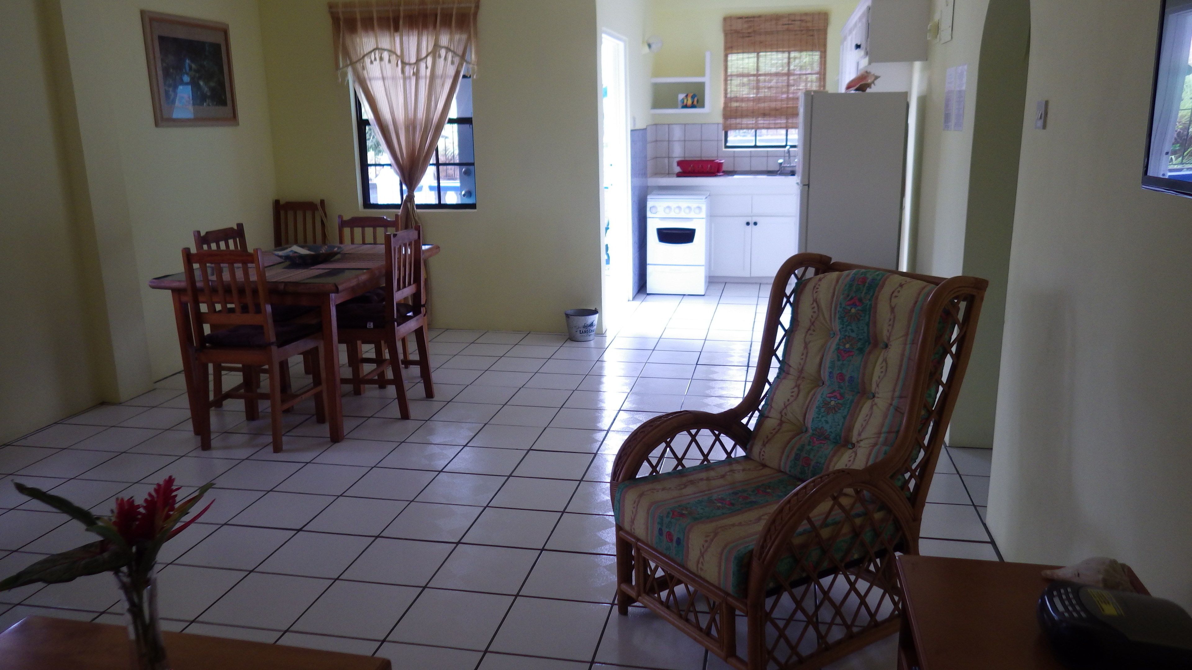 A dining area with a wooden table and chairs, a patterned armchair, and a tiled floor.