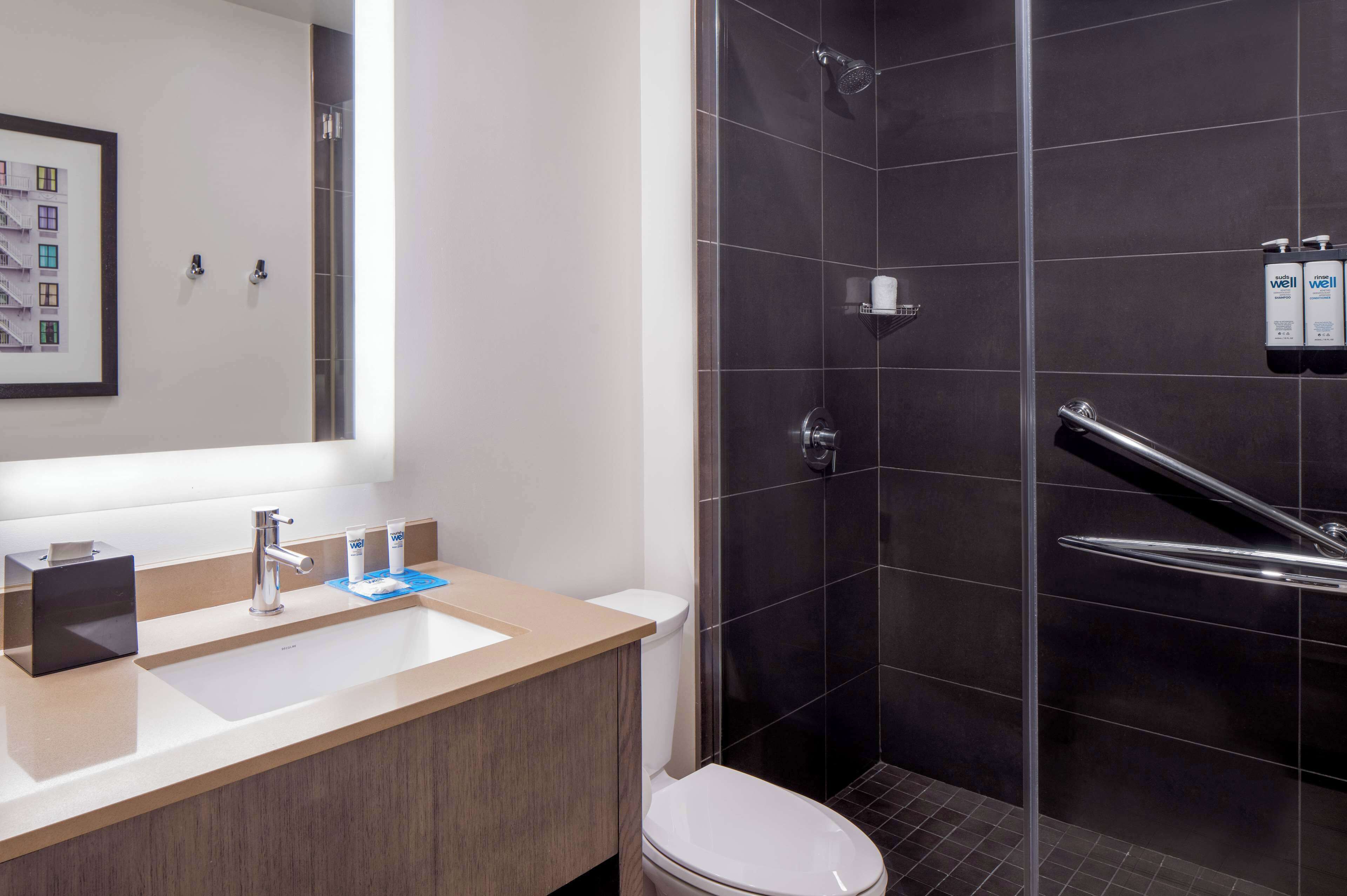 A modern bathroom with a large mirror, a sink, and a shower area.