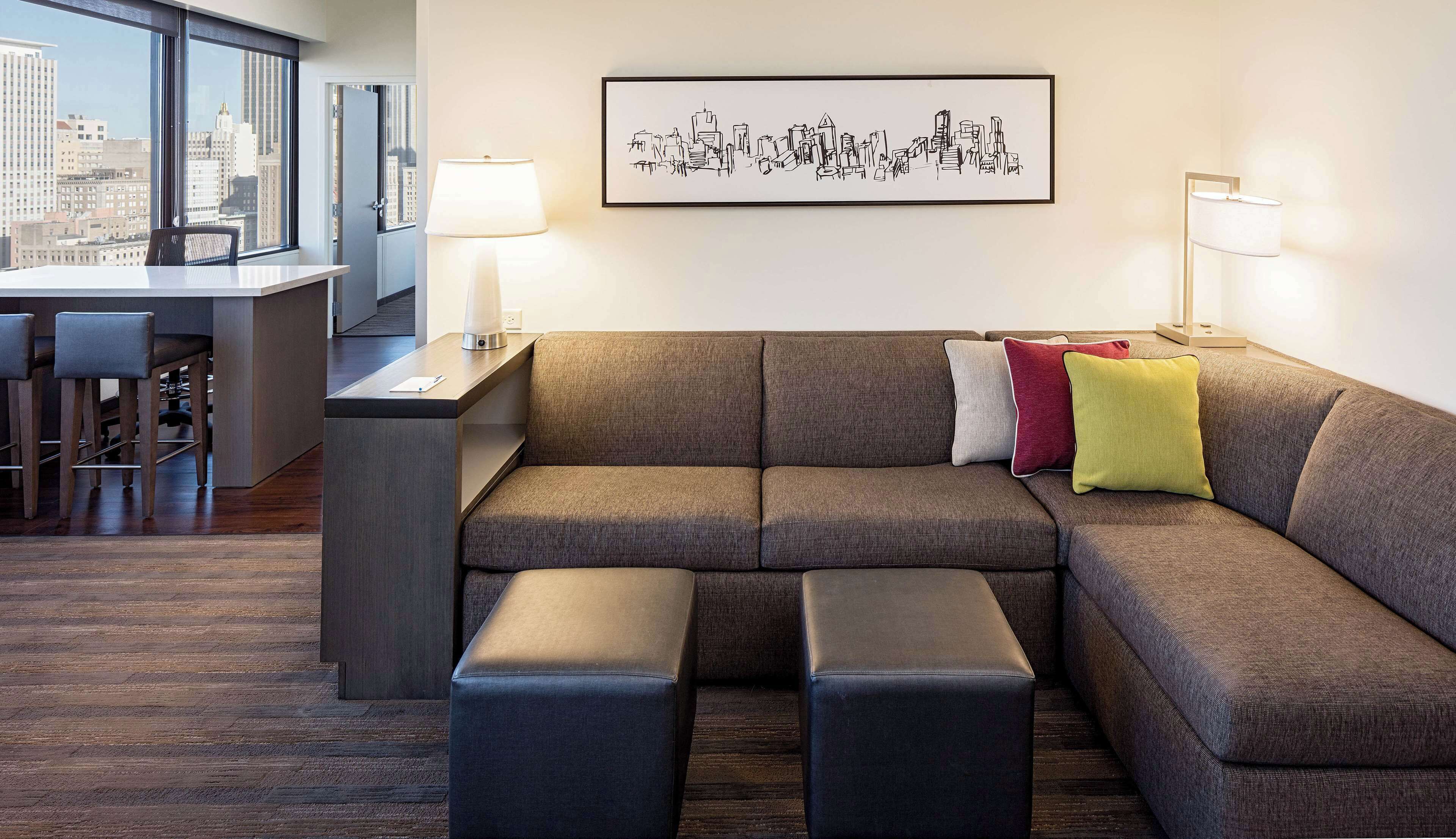 A modern living room with a sectional sofa, a coffee table, and a cityscape artwork on the wall.