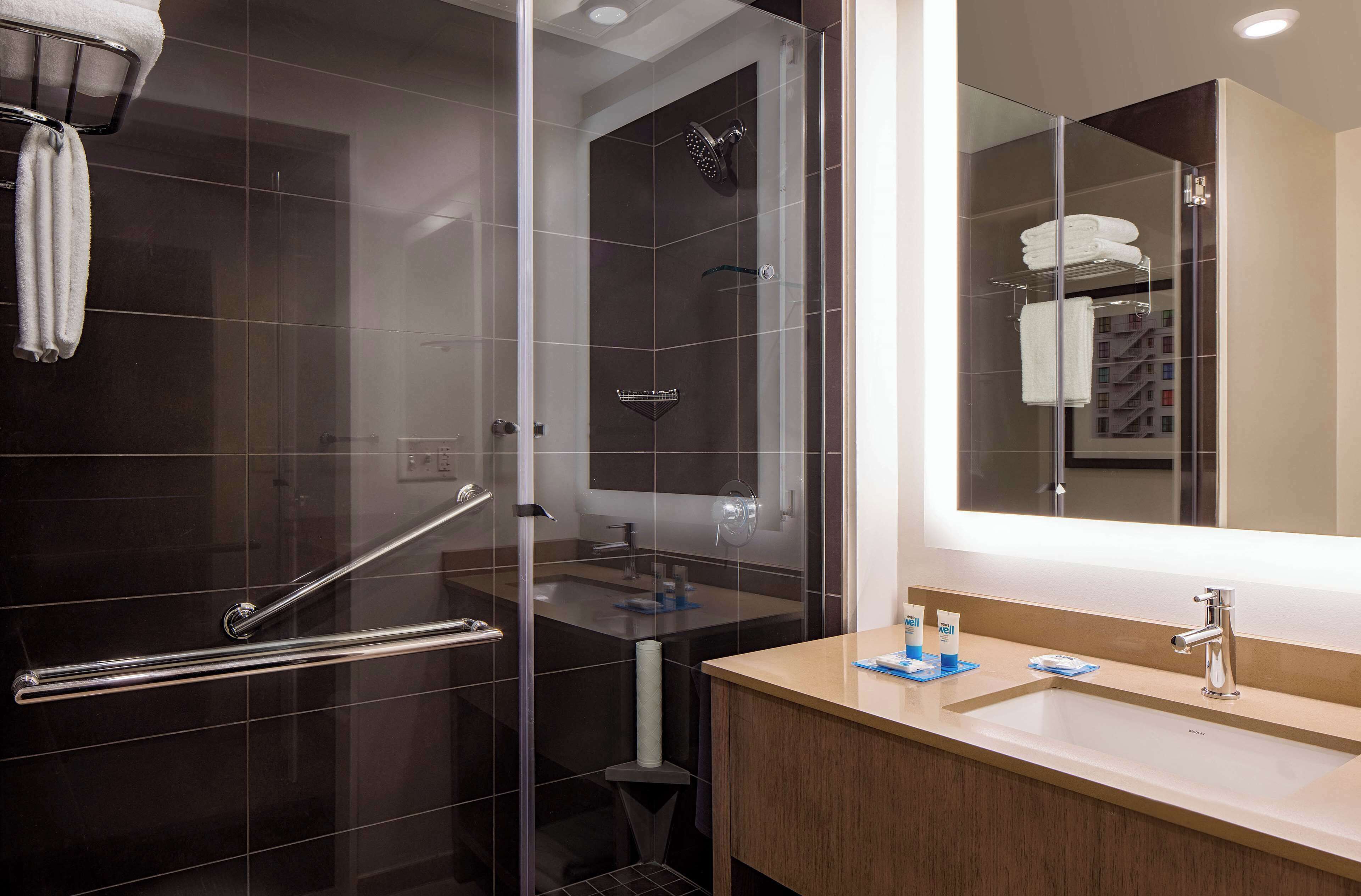 A modern bathroom with a glass-enclosed shower, a vanity with a sink, and a large mirror.