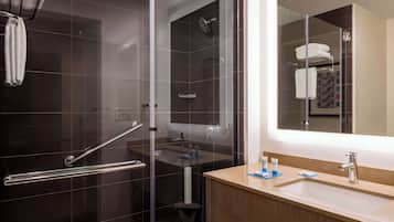 A modern bathroom with a glass-enclosed shower, a vanity with a sink, and a large mirror.