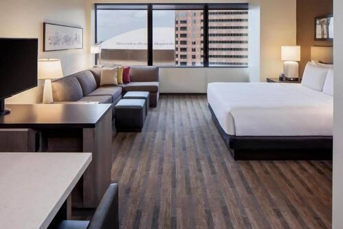 Une chambre d’hôtel avec un lit, un canapé, un bureau et une télévision.