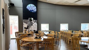 A spacious room with multiple wooden tables and chairs arranged for dining.