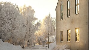 A snow-covered landscape with a building featuring multiple windows and a pathway.