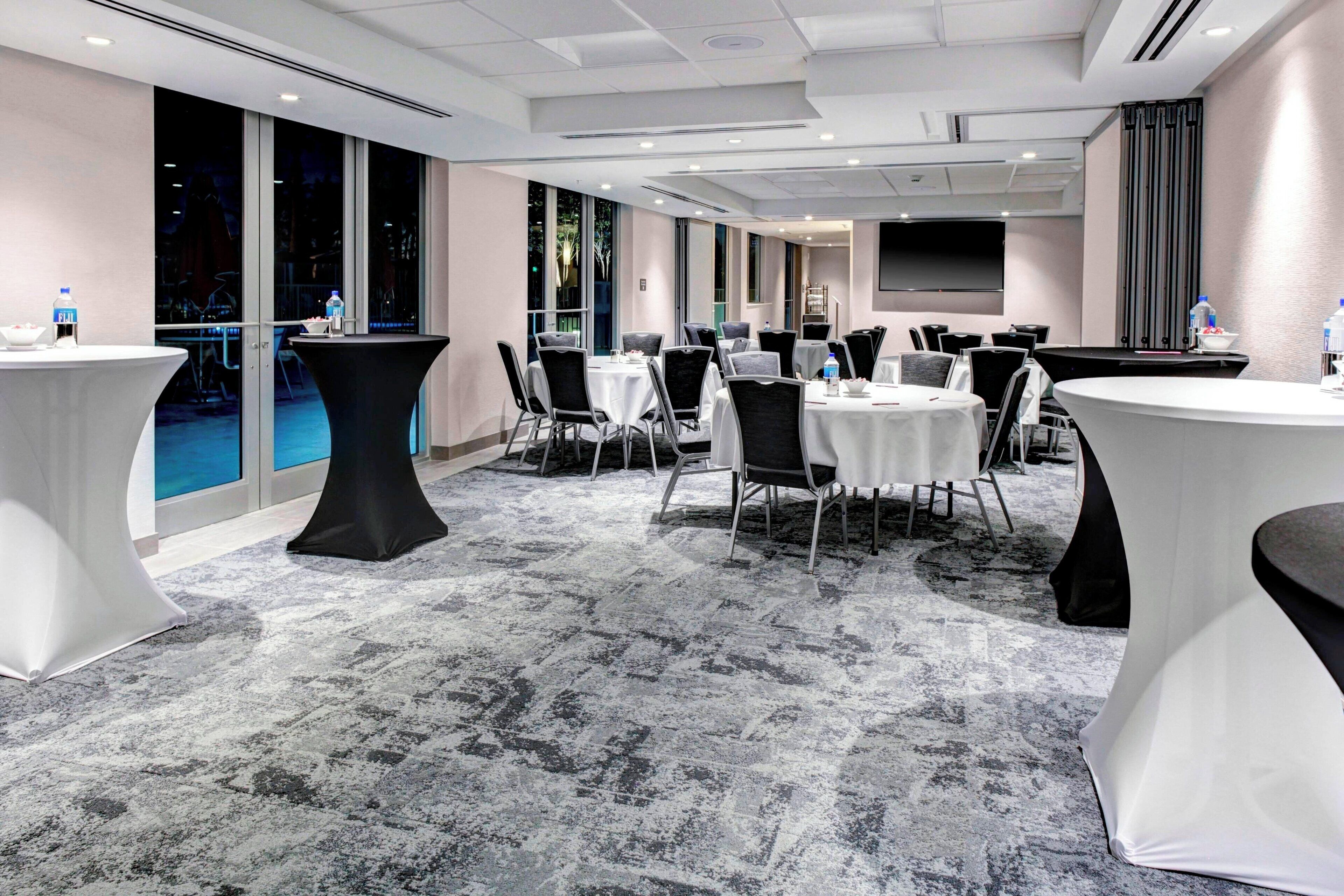 A conference room with round tables, chairs, and a large screen.