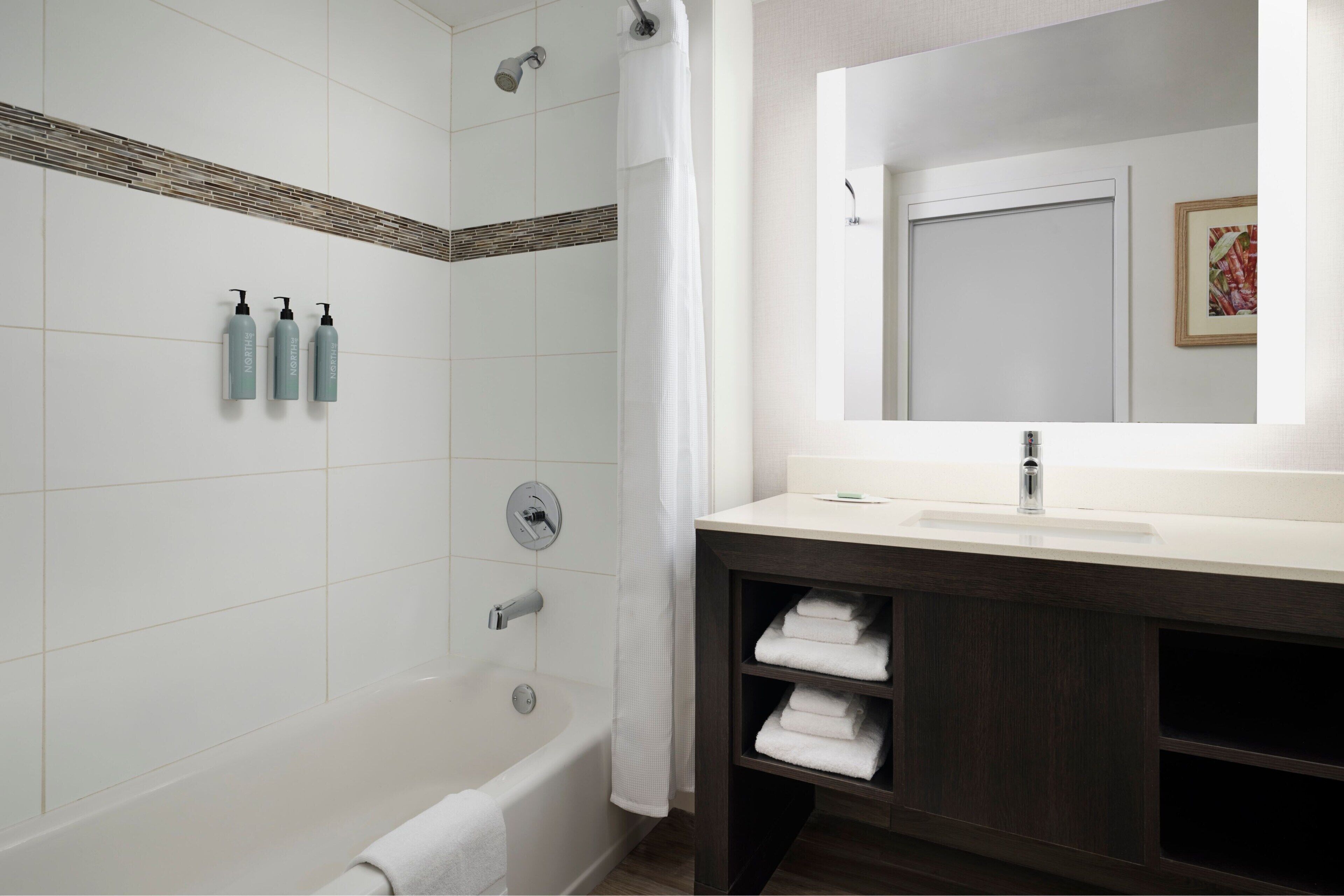 Un baño moderno con bañera, ducha y tocador con espejo.