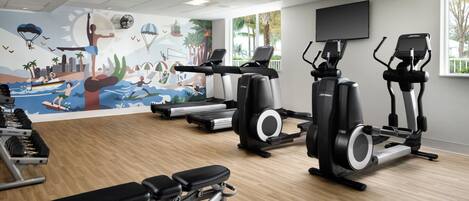 A gym with treadmills, elliptical machines, and weight benches.