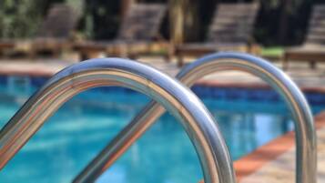 Una piscina con barandillas de metal y sillones de descanso al fondo.