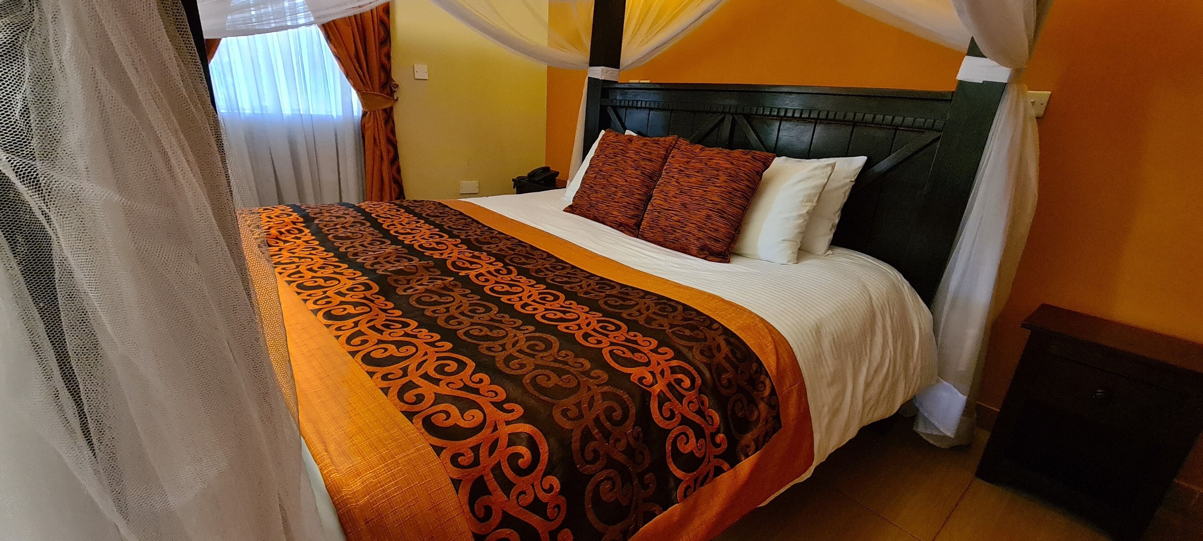 A bed with a patterned bedspread, a headboard, and a nightstand with a phone.
