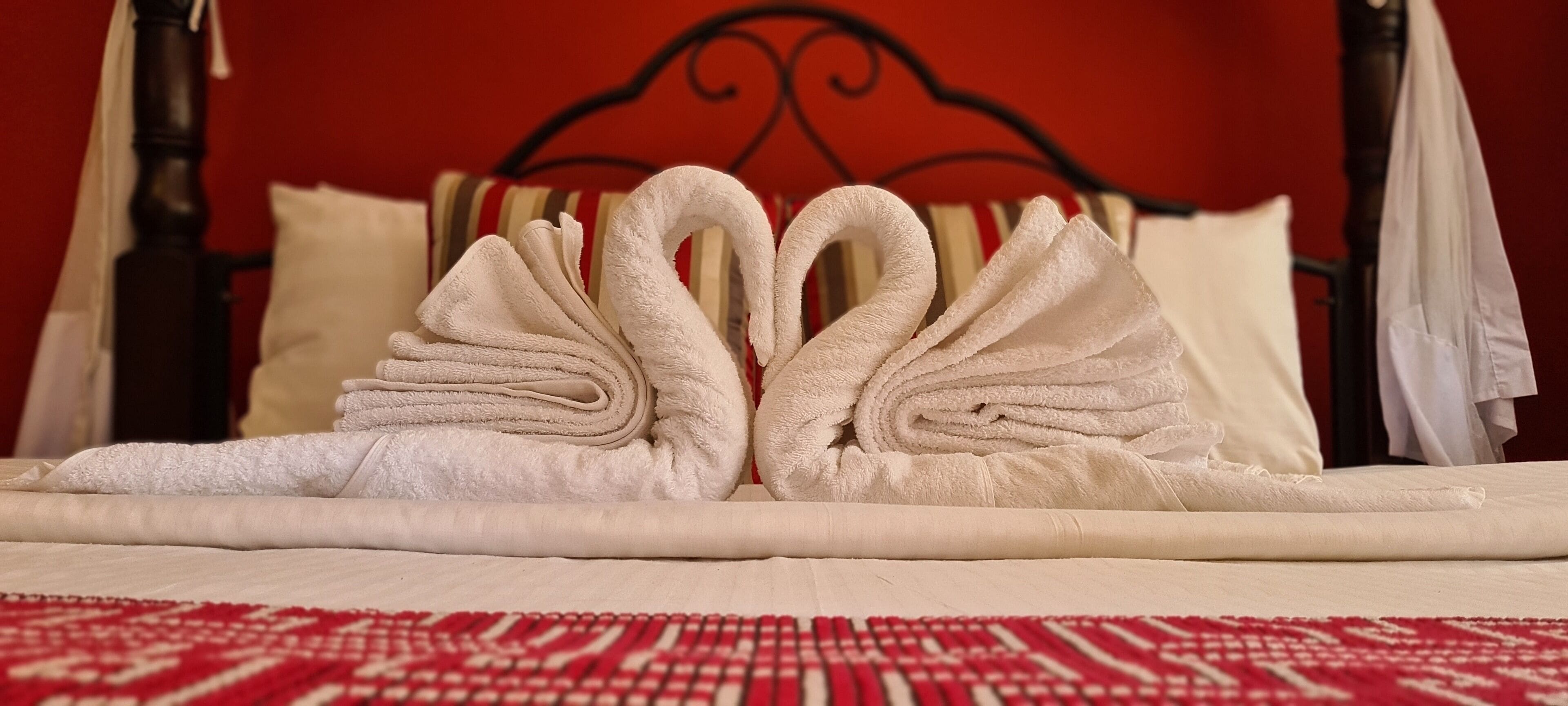 A bed with towels arranged in the shape of swans.