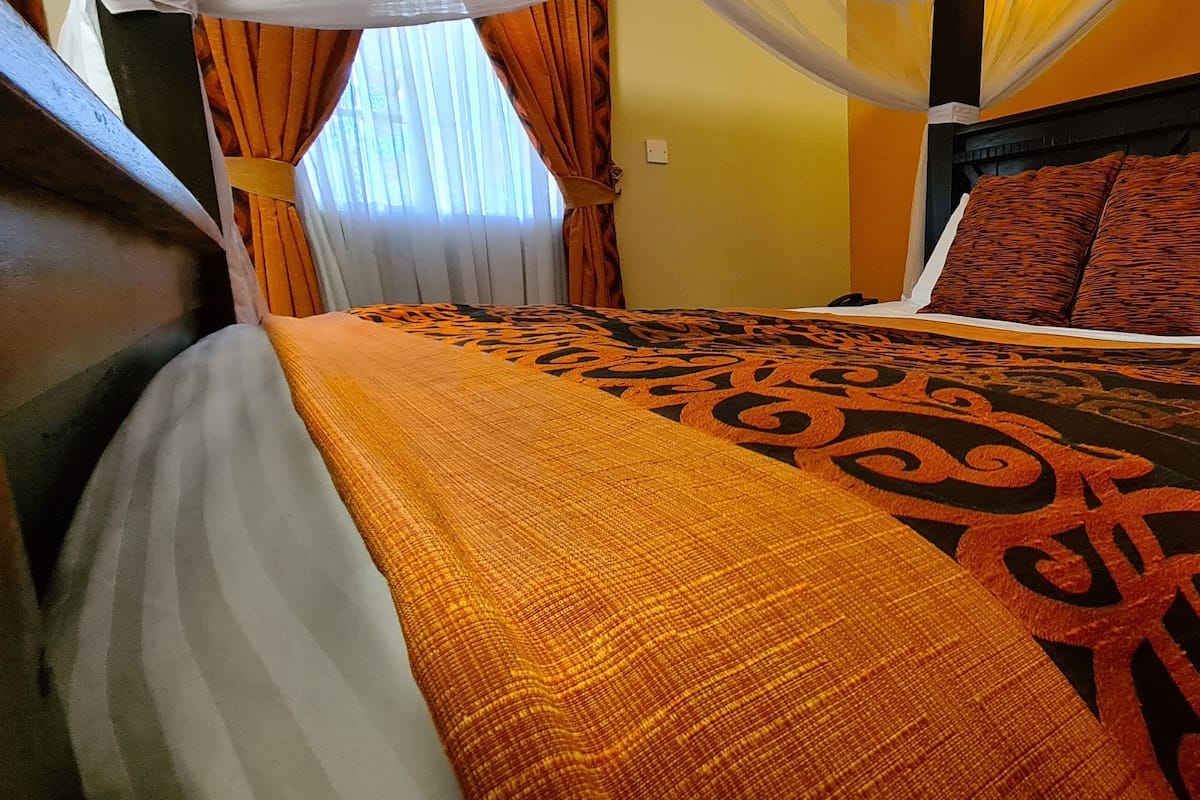 A hotel room with a bed, curtains, and a canopy.