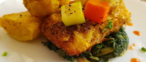 A plated dish with a golden-brown crust, diced vegetables, and a sauce.