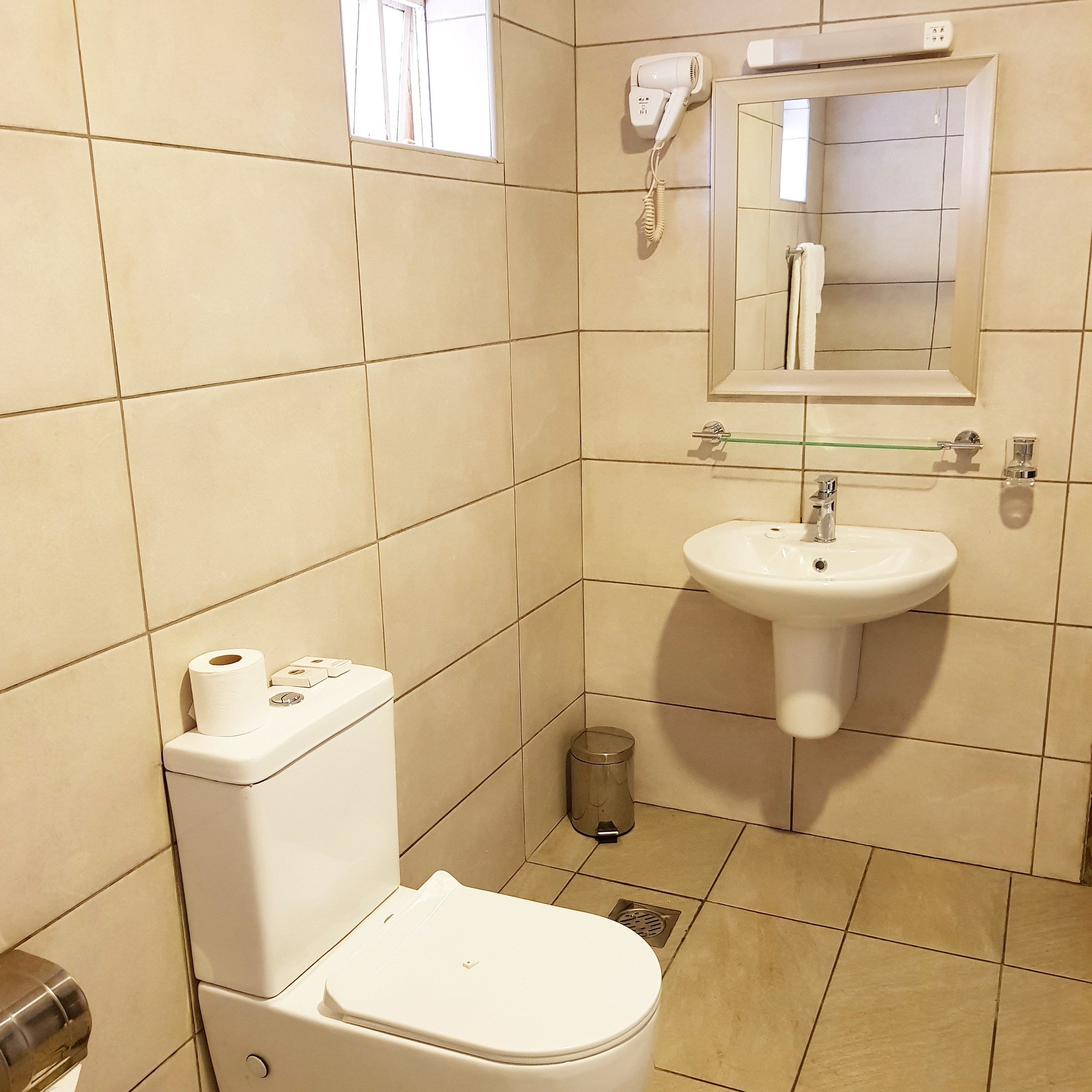 A bathroom with a toilet, sink, and a window.