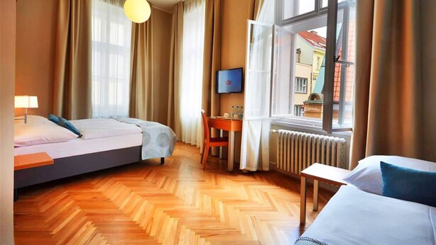 Une chambre d’hôtel équipée d’un lit, d’un bureau, d’une chaise, d’une télévision et d’une fenêtre avec des rideaux.
