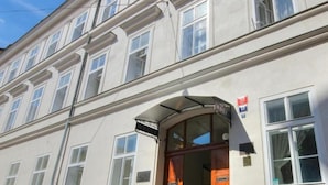 Un bâtiment au style architectural classique, doté d’une entrée imposante surmontée d’un auvent incurvé et d’une enseigne placée au-dessus de la porte.