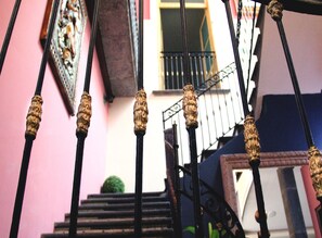 Un escalier orné de balustres noirs et un mur rose.