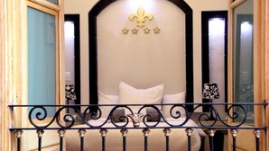 A bedroom with a bed, a decorative headboard, and a window with curtains. - Villahernan Hotel (Puebla)