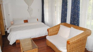 Un dormitorio con una cama, un sofá de mimbre y una mesita.