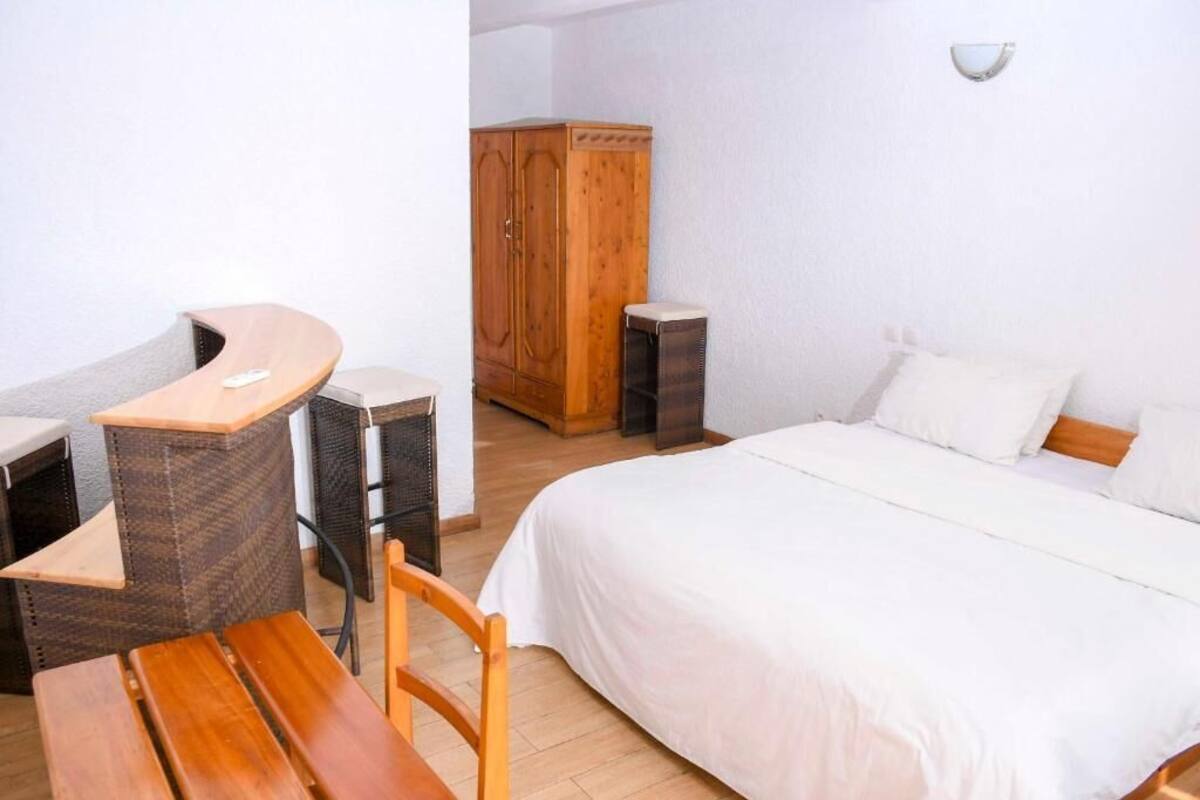 Ein Schlafzimmer mit einem Bett, einem Holzschrank, einem kleinen Tisch und einem Stuhl.