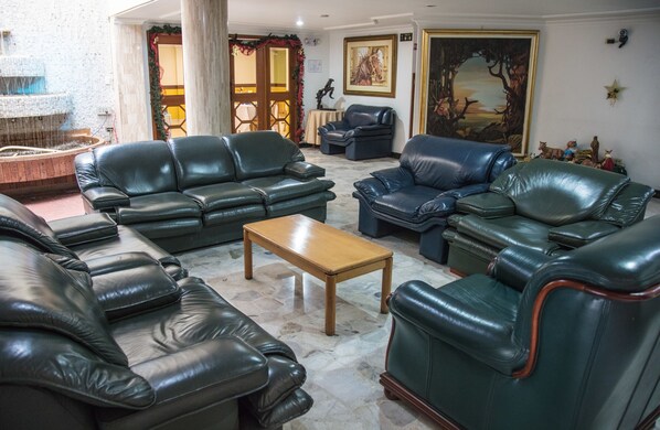 A spacious living room with leather sofas, a wooden coffee table, and a fountain.