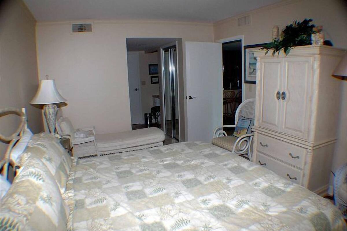 Un dormitorio con cama, cómoda, silla y espejo.