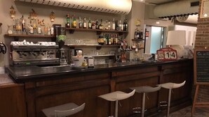 Un espace bar avec un comptoir, des tabourets et des étagères remplies de bouteilles.