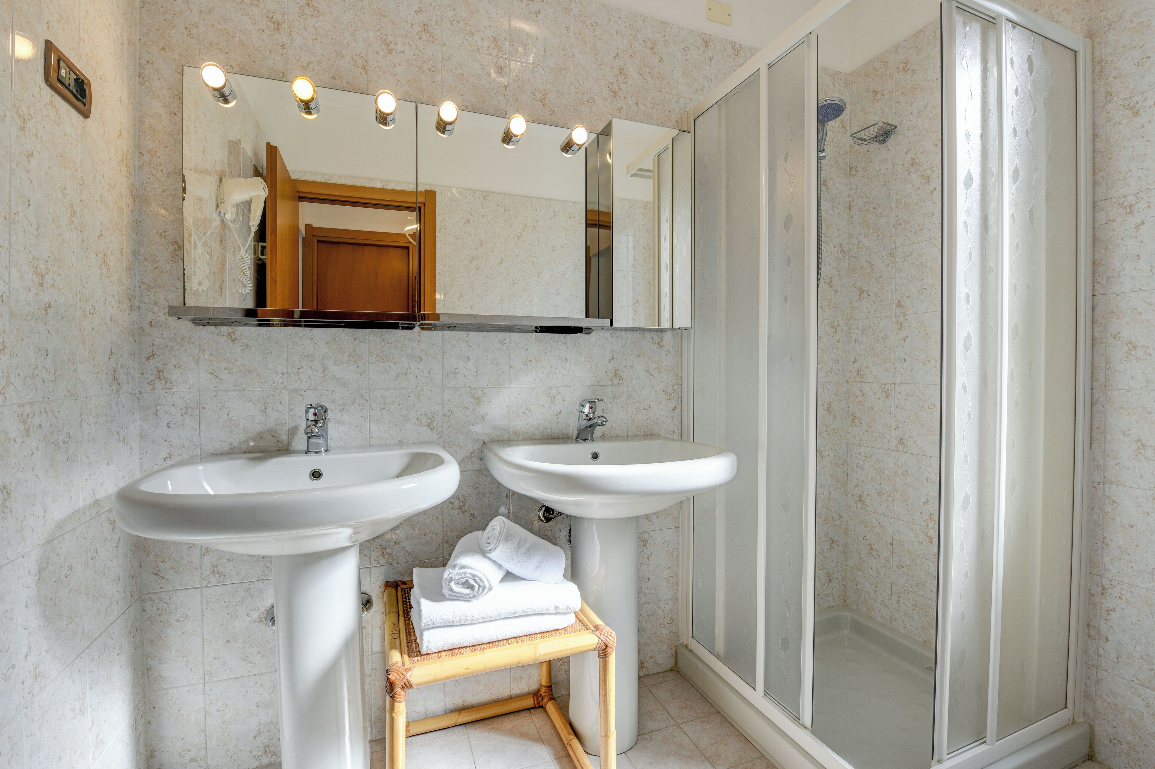 A bathroom with two sinks, a mirror, and a shower.