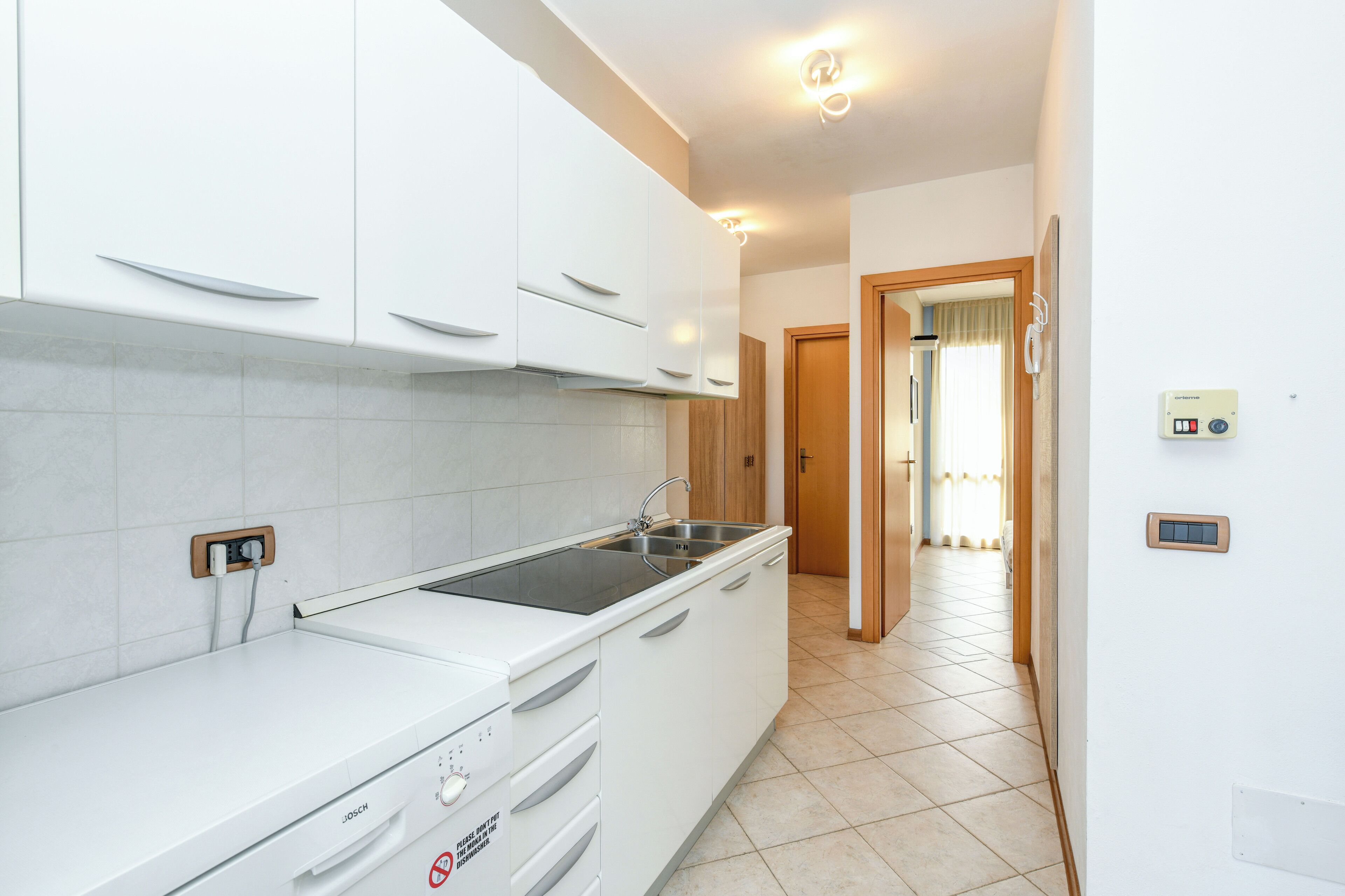 Une cuisine moderne avec des meubles blancs, une cuisinière encastrée et un évier.