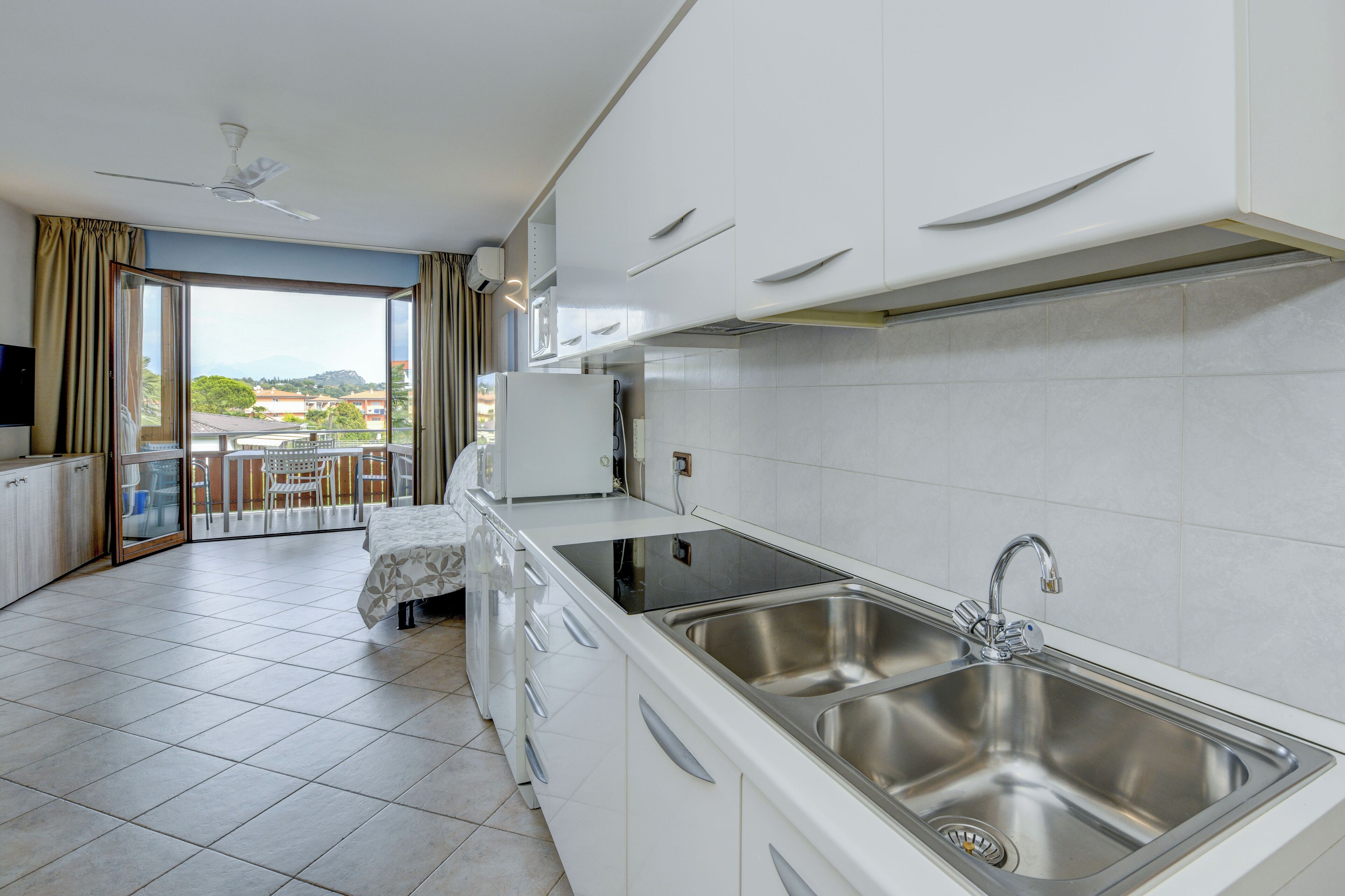 Una cocina moderna con armarios blancos, un lavamanos de acero inoxidable y un horno empotrado.