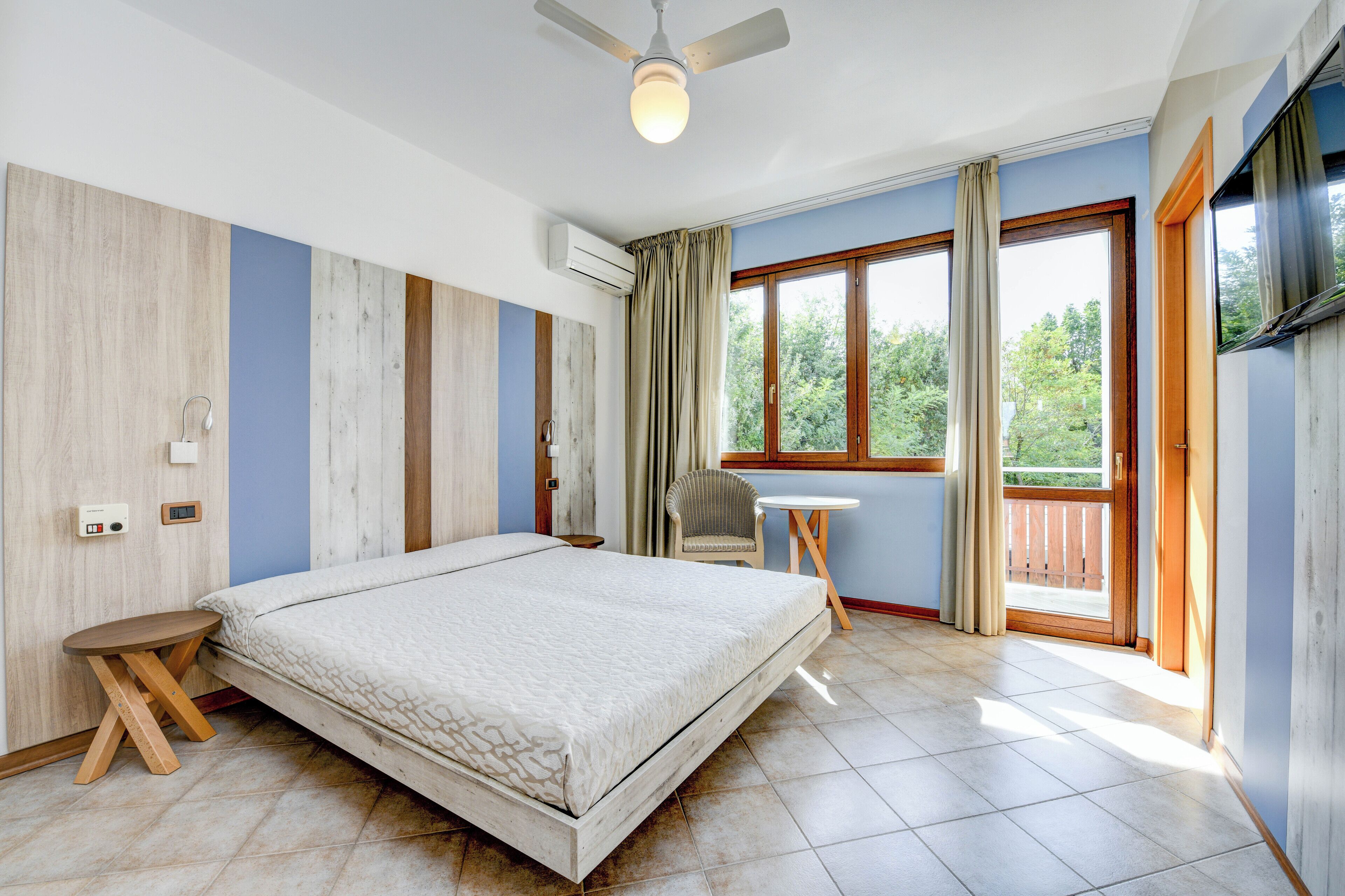 Une chambre à coucher avec un lit, une chaise, une petite table et un ventilateur de plafond.