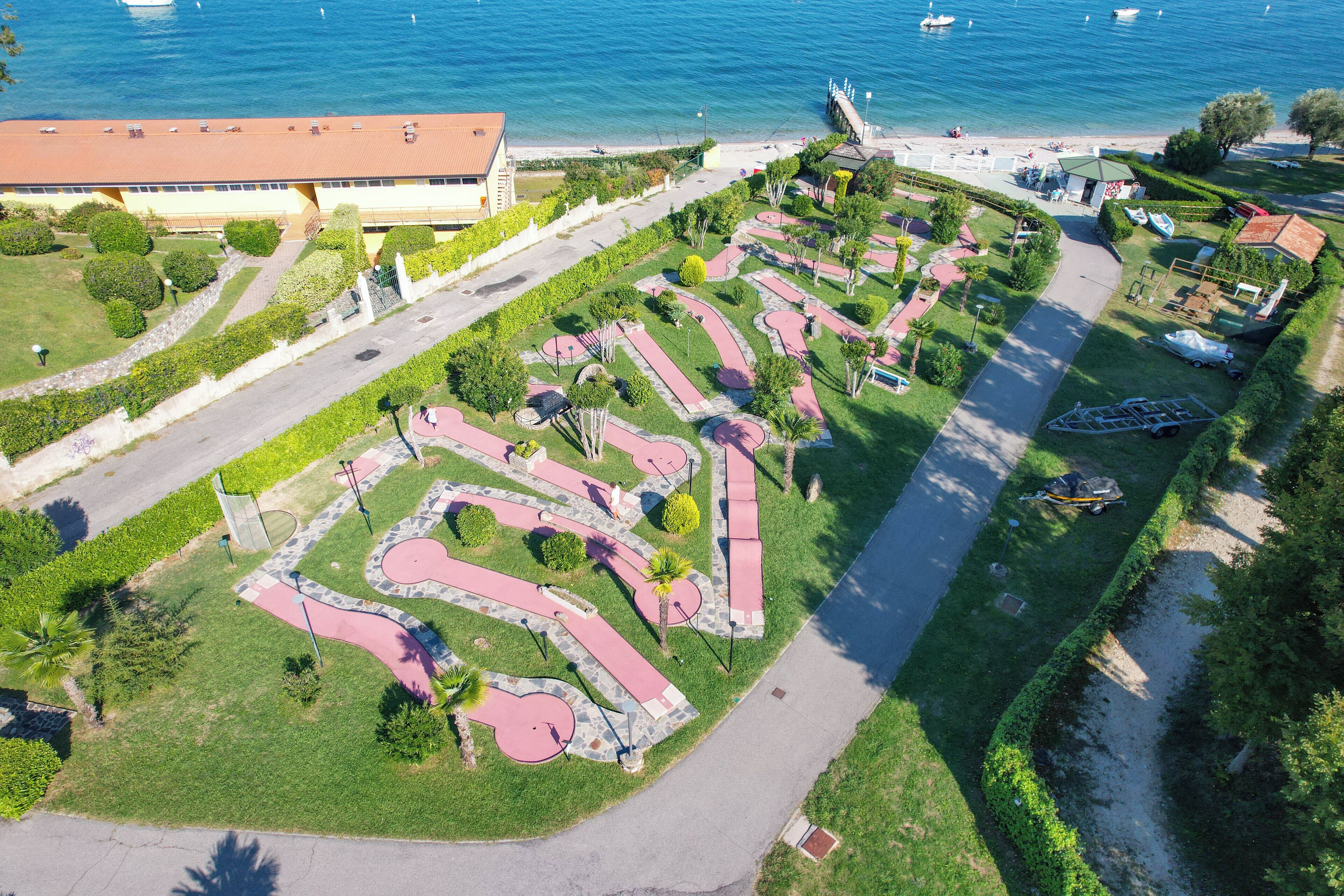 Vista aérea de un área ajardinada con senderos, un edificio y una playa.
