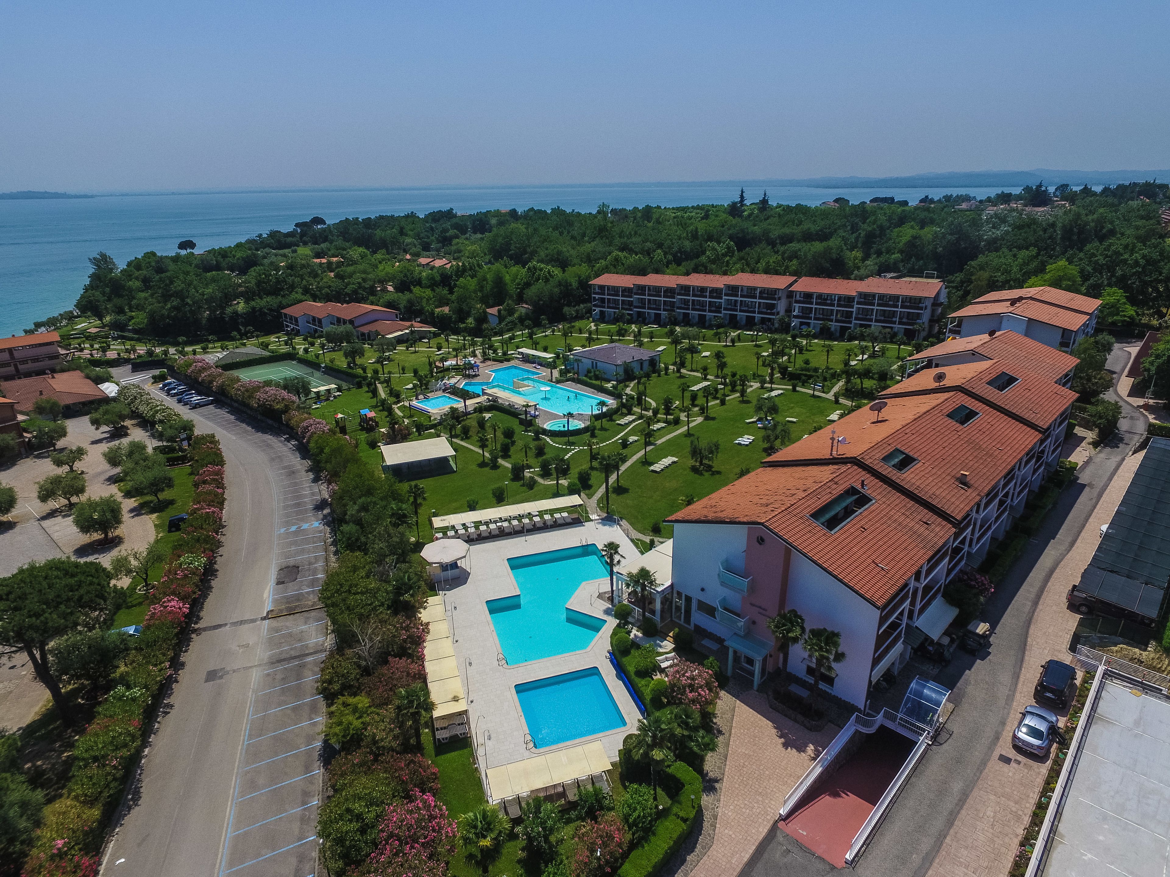 Eine Luftaufnahme eines Resorts mit mehreren Schwimmbecken, üppiger Vegetation und Blick auf das Meer.