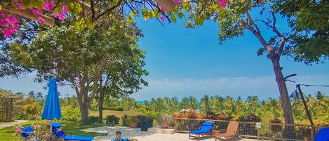 A swimming pool area with lounge chairs and a person relaxing by the pool.