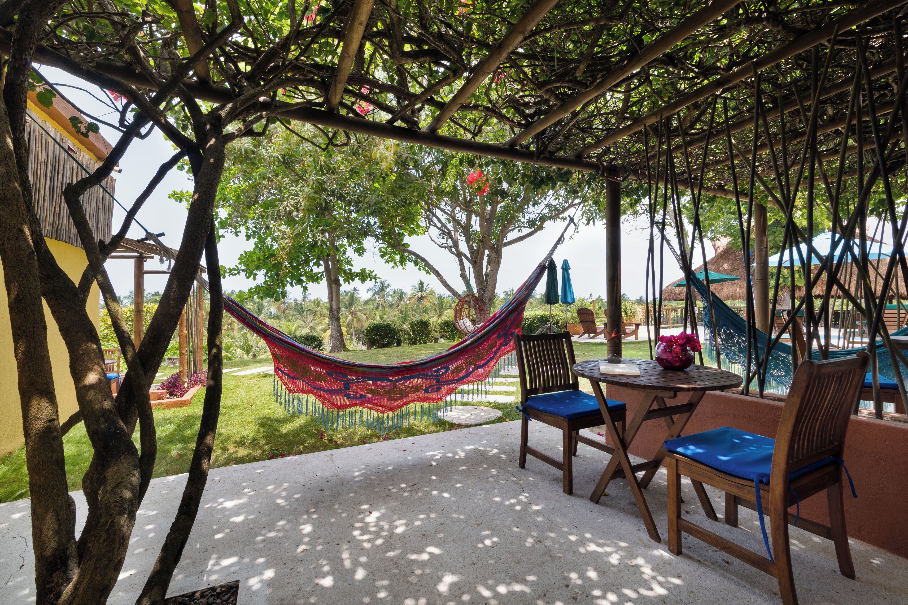A covered outdoor seating area with a hammock, chairs, and a table.