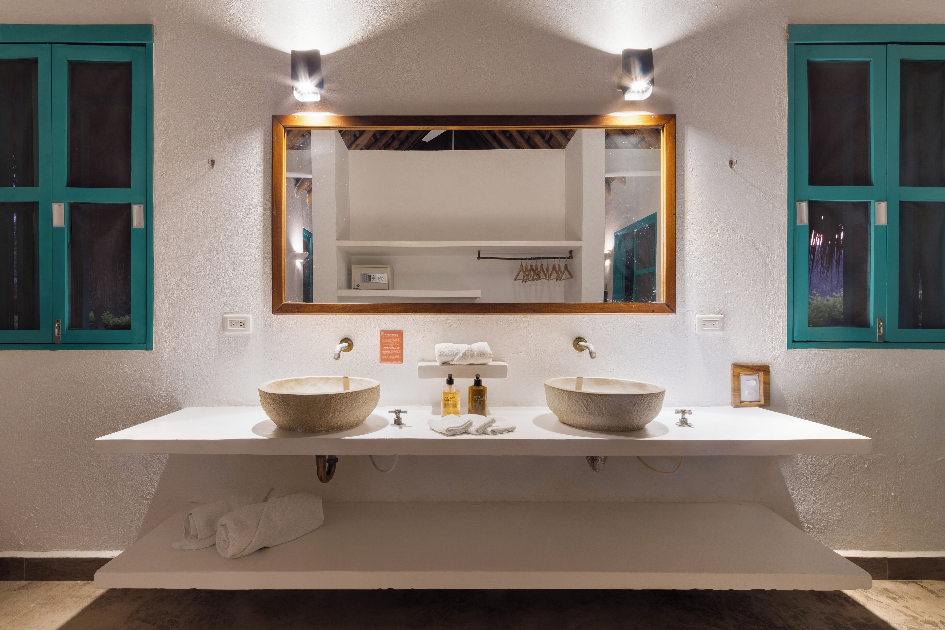 A bathroom with two large stone sinks, a white vanity, and a large mirror.