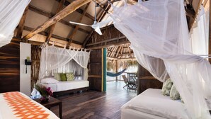 A room with a bed, a small table with a vase of flowers, a hammock, and a ceiling fan. - Aite Hotel (Dibulla)