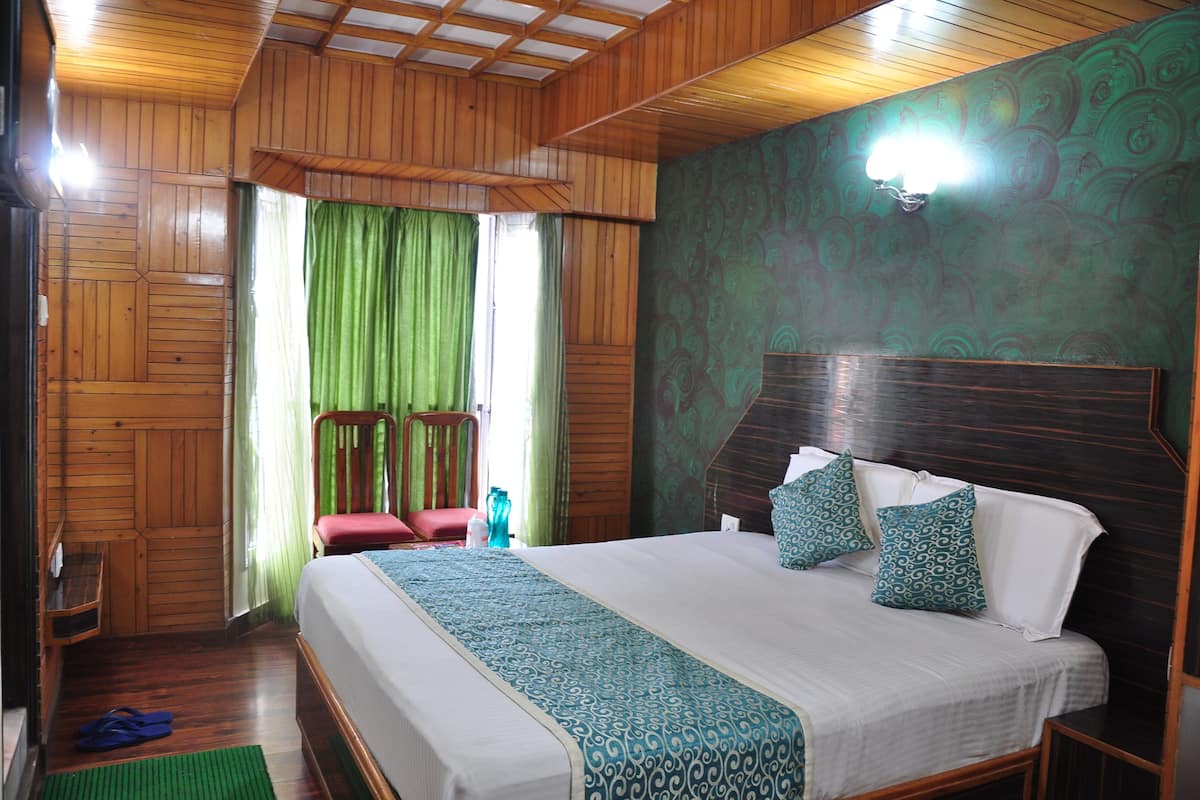 A wooden-paneled room with a bed, green curtains, and a wall-mounted light fixture.