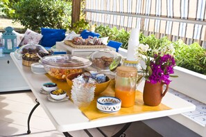 A buffet table with various food items and a pitcher of orange juice. - La Sirena (Lipari)