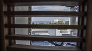 A view through window blinds of a rooftop terrace with a pool, a white building, and a clear sky. - La Sirena (Lipari)