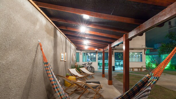 Un espacio al aire libre techado con una hamaca, sillas de madera y una bicicleta.