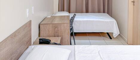 Une chambre d’hôtel avec deux lits, un climatiseur fixé au plafond, une lampe fixée au mur et une armoire en bois.