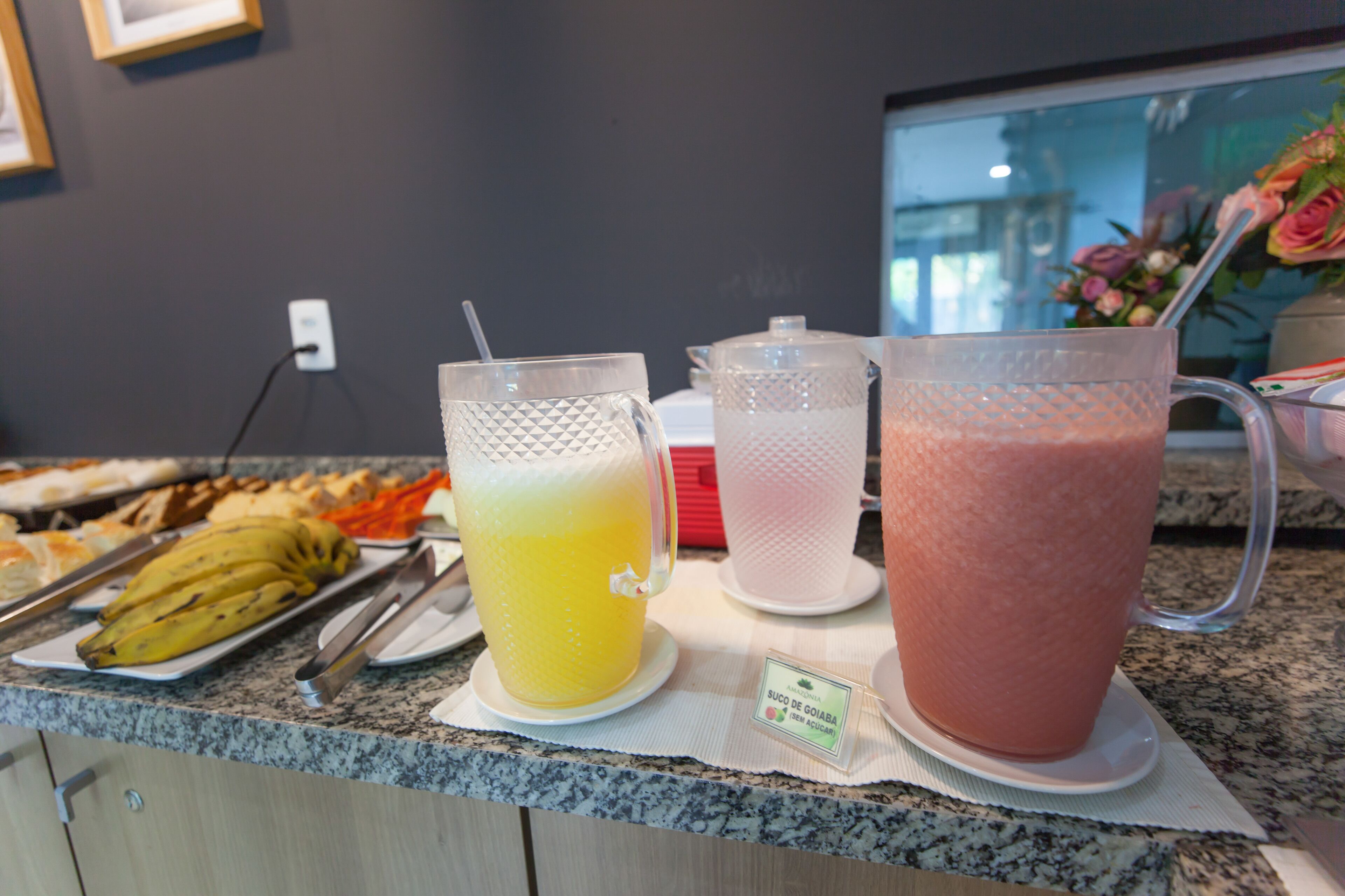 A buffet counter with a variety of food items and two large beverage dispensers.