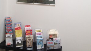 Un mur orné d’une affiche encadrée représentant le paysage urbain de Florence, et une étagère contenant des brochures de voyage.