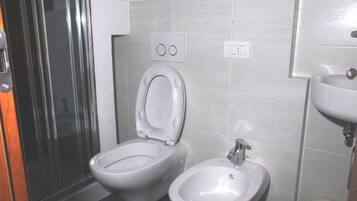 Un baño con inodoro, bidé y lavamanos.