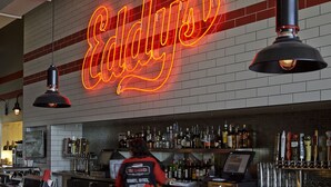 A bar area with a neon sign reading "Eddy's" and a bartender at work. - Eddy's Resort (Onamia)