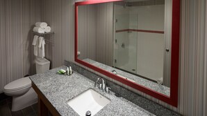 A bathroom with a large mirror, a sink, a toilet, and a shower.