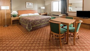 Een hotelkamer met een bed, een bureau met stoel, een televisie en een raam met gordijnen.