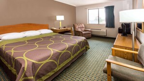 A hotel room with a large bed, a desk with a lamp, a chair, a TV, and a window with curtains. - Super 8 by Wyndham St. Charles (SAINT CHARLES)